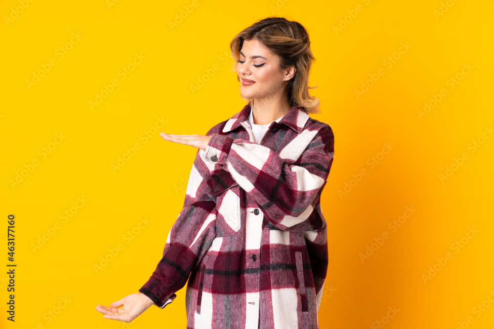 Young Russian woman isolated on yellow background holding copyspace to insert an ad Young Russian woman isolated on yellow background holding copyspace to insert an ad