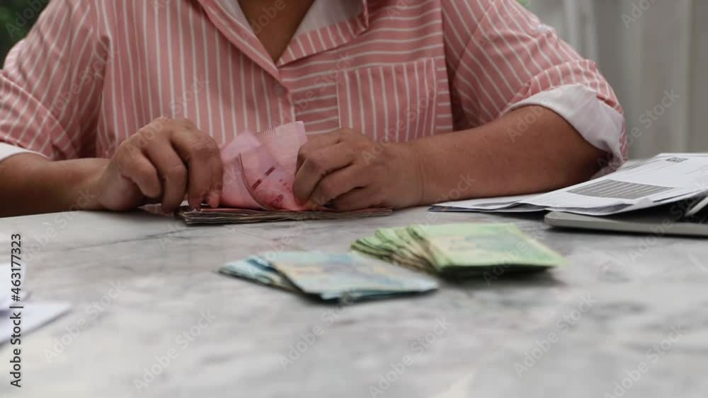 Hands of a retired woman counting the banknotes accumulated on the table to secure her future health insurance. Hands of a retired woman counting the banknotes accumulated on the table to secure her future health insurance.