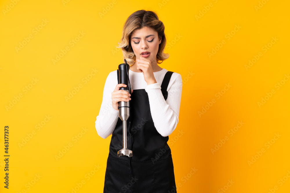 Girl using hand blender isolated on yellow background coughing a lot Girl using hand blender isolated on yellow background coughing a lot