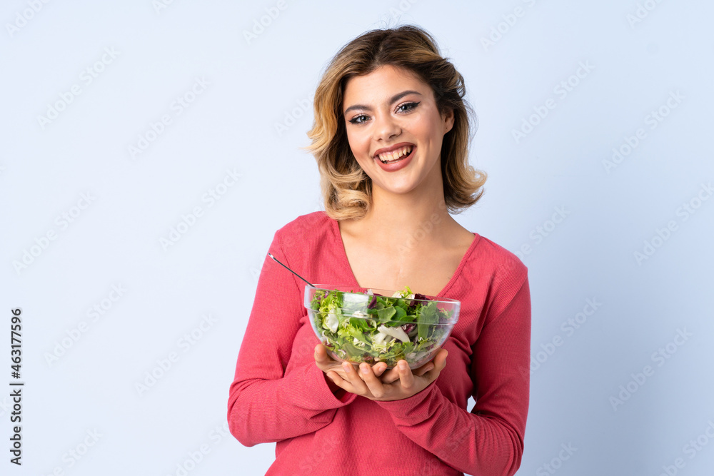 Teenager woman with salad isolated on blue background Teenager woman with salad isolated on blue background