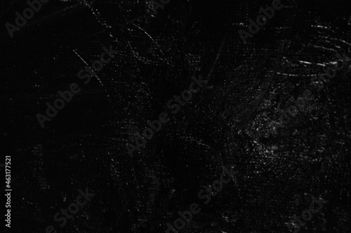 Dark creative background - rough linen canvas unevenly covered with black primer, reflections of light. Toning, blurring, selective focus.