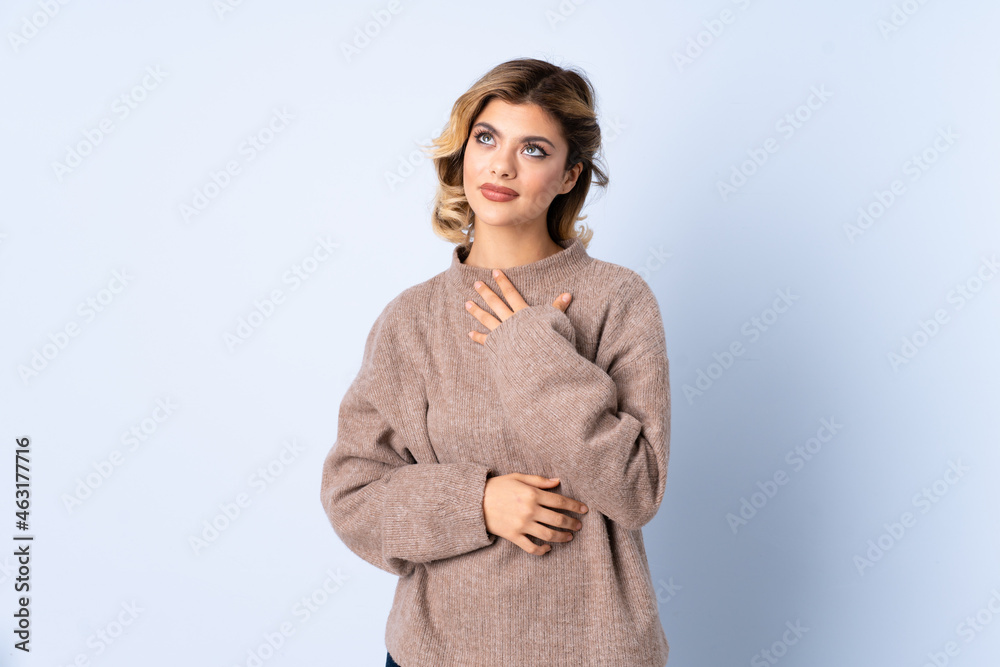 Young Russian woman isolated on blue background looking up while smiling Young Russian woman isolated on blue background looking up while smiling