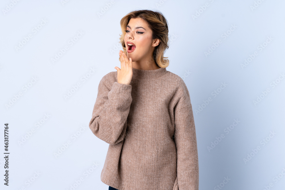 Young Russian woman isolated on blue background yawning and covering wide open mouth with hand Young Russian woman isolated on blue background yawning and covering wide open mouth with hand