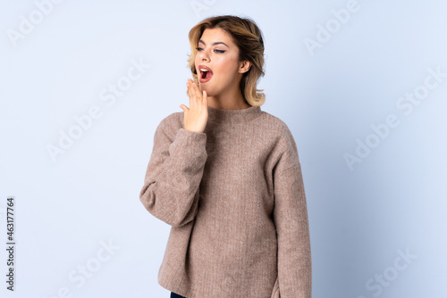 Young Russian woman isolated on blue background yawning and covering wide open mouth with hand