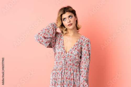 Young Russian woman isolated on pink background having doubts