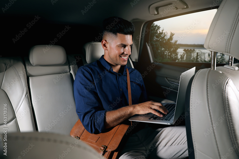 Businessman working on laptop in modern taxi