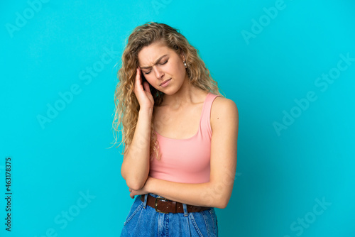 Young blonde woman isolated on blue background with headache