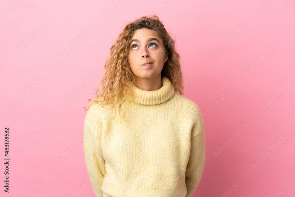 Young blonde woman isolated on pink background and looking up Young blonde woman isolated on pink background and looking up