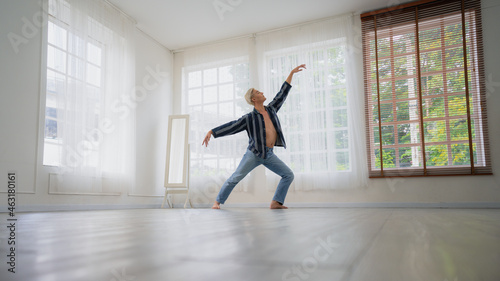 Asian Male ballet dancer of dancing in room with glass windows and white curtain. Exercise at home with new normal lifestyle.