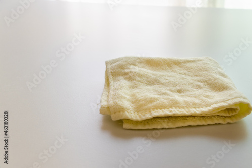 テーブルの上にたたんで置かれた淡い黄色のタオル