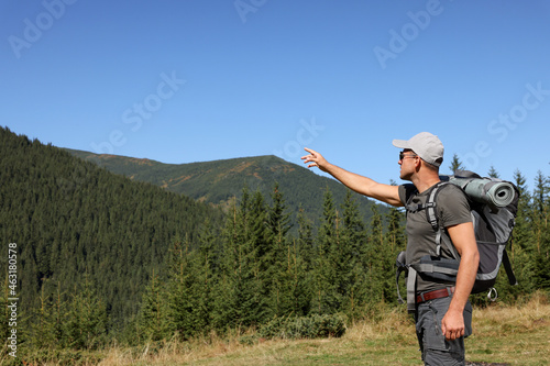 Tourist with backpack in mountains on sunny day. Space for text