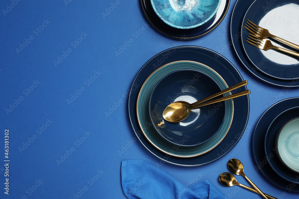 Clean dishware and cutlery on blue background, flat lay. Space for text Clean dishware and cutlery on blue background, flat lay. Space for text