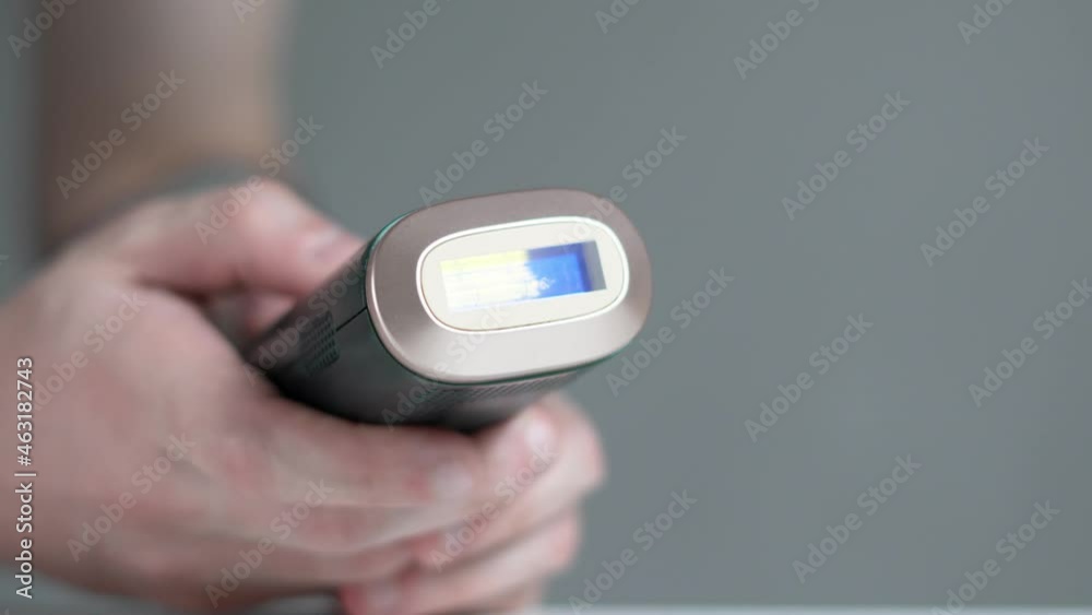 Young and athletic man applying or holding laser hair removal device. The device removes the hair professionally at home comfort. An alternative way to permanently remove body hair. Young and athletic man applying or holding laser hair removal device. The device removes the hair professionally at home comfort. An alternative way to permanently remove body hair.