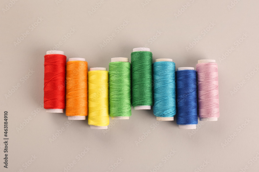 Different colorful sewing threads on light grey background, flat lay Different colorful sewing threads on light grey background, flat lay