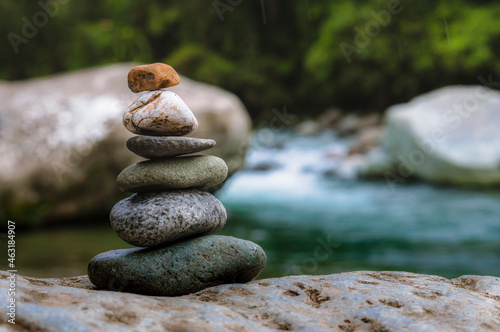 Rocks stacked in balance in a peaceful rainforest on the side of a river in a national park of Costa Rica photo