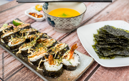 A plate of Spicy Shrimp Rolls, served with sheets of Nori seaweed and tasty soup. photo