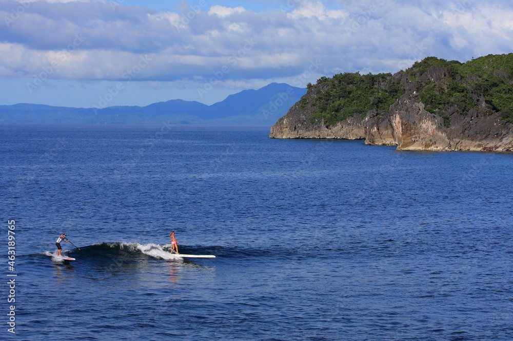 girl surfing an SUP standup paddle board in tropical blue ocean. 