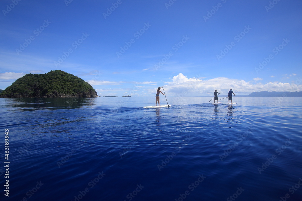 people paddling sup standup paddle boards in calm blue waters. Philippines