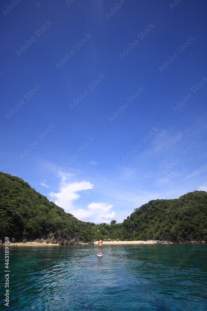 girl paddling a SUP standup paddle board in tropical blue ocean. 