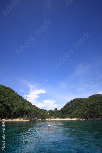 girl paddling a SUP standup paddle board in tropical blue ocean. 