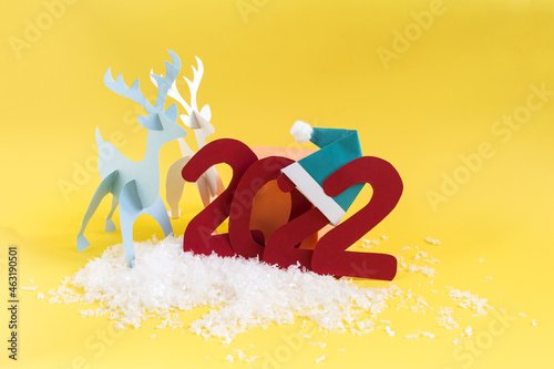 Origami paper deer and the numbers 2022 on a bright yellow background. A bright New Year's card.
