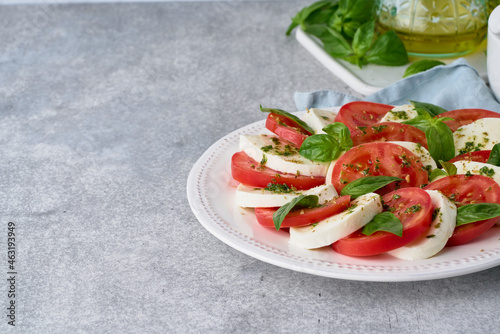 Side view of italian caprese salad with mozarella, tomatoes, olive oil and basil leaves. Vegetarian starter full of antioxidant and vitamins. Homemade national light meal. Horizontal, copy space