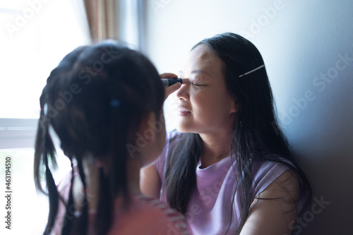 Asian little daughter doing make up her mom. Concept of love and connection of mother and kid.