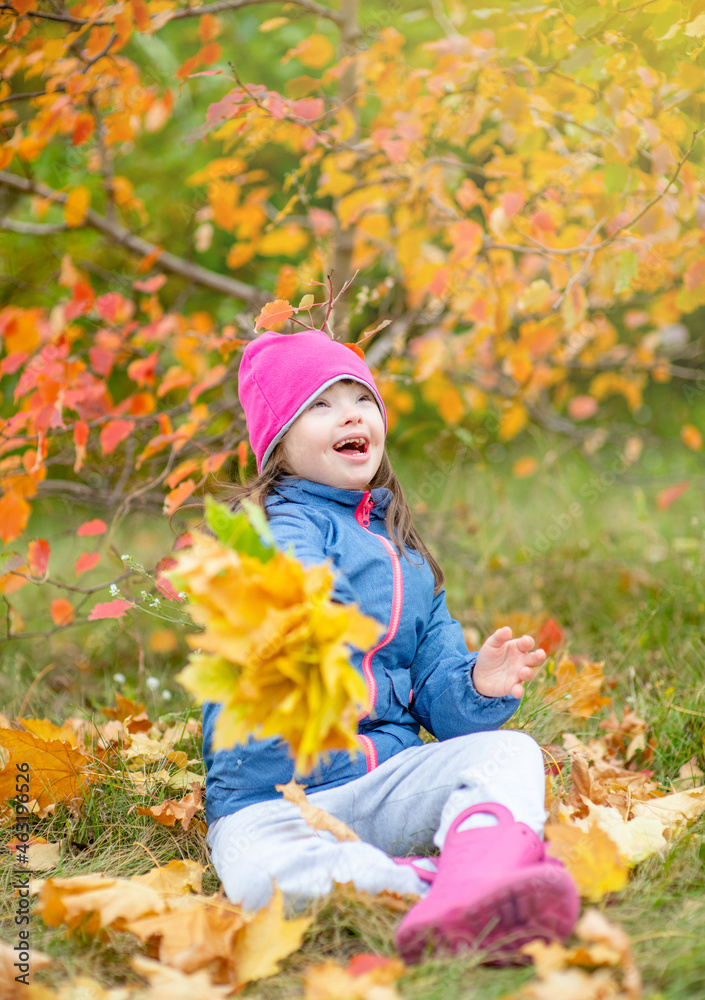 Surprised young girl with Downs syndrome sits on autumn leaves Surprised young girl with Downs syndrome sits on autumn leaves