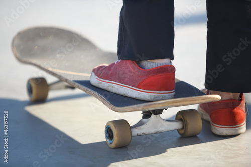 Fotografie, Obraz Teen skater girl standing on old skate board deck in skatepark ready to skate