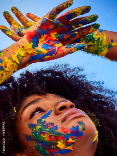 Little girl enjoying nature with her face painted in different colors      