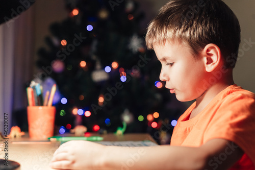 7 yeas old boy sitting at desk and reading book photo