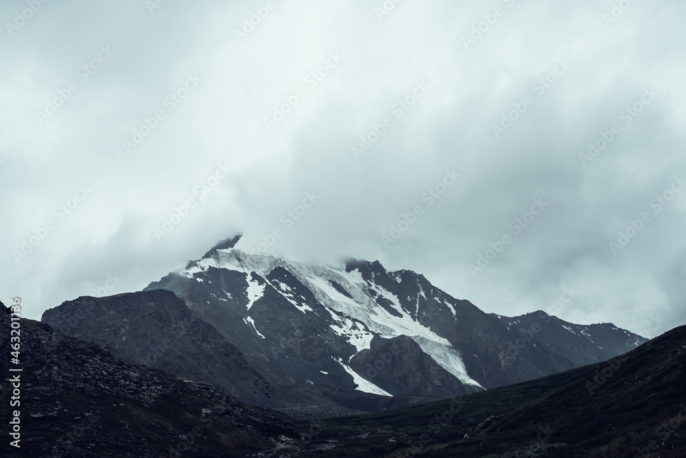 Minimalist monochrome atmospheric mountains landscape with big snowy mountain top in low clouds. Awesome minimal scenery with glacier on rocks. Black white high mountain pinnacle with snow in clouds. Minimalist monochrome atmospheric mountains landscape with big snowy mountain top in low clouds. Awesome minimal scenery with glacier on rocks. Black white high mountain pinnacle with snow in clouds.