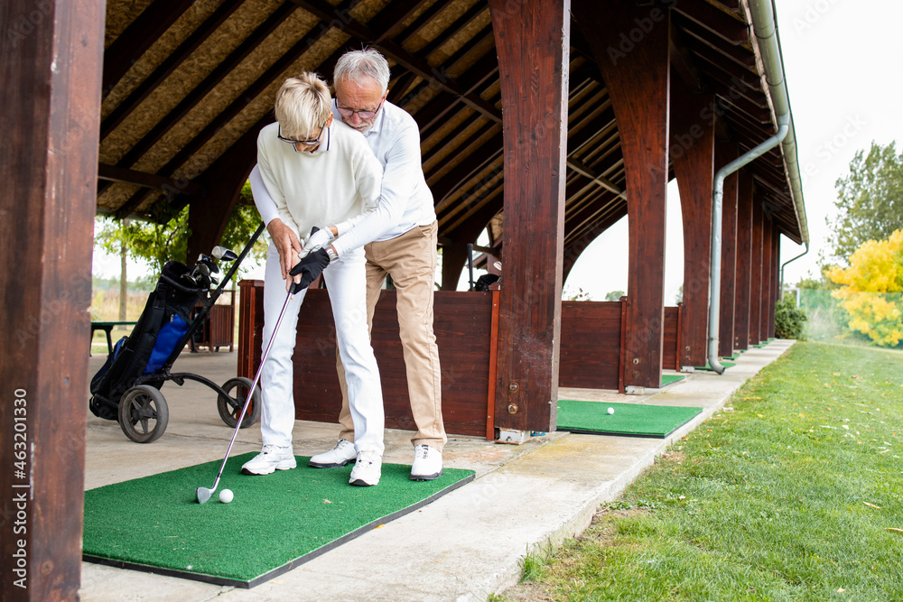 Senior people in retirement learning how to play golf on golf course.