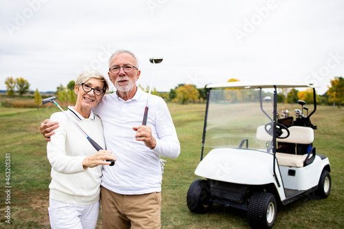 Portrait of caucasian senior golfers with golf clubs standing on the golf course.