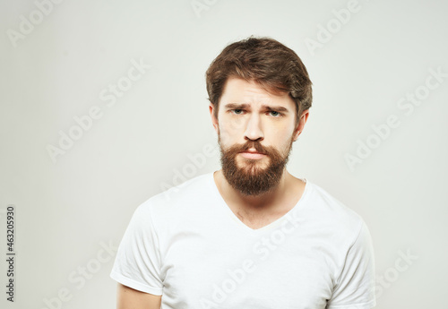 bearded man in a white t-shirt irritated facial expression light background © SHOTPRIME STUDIO