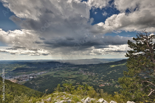 Beautiful view from the mountains towards the valley and the sea in the background. Rainy clouds in the blue sky. Vipava, Slovenia.
