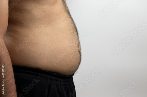 Side view photo of a shirtless man with a rather fat, bulging body and hair on the chest, abdomen, on a white background with space for text.