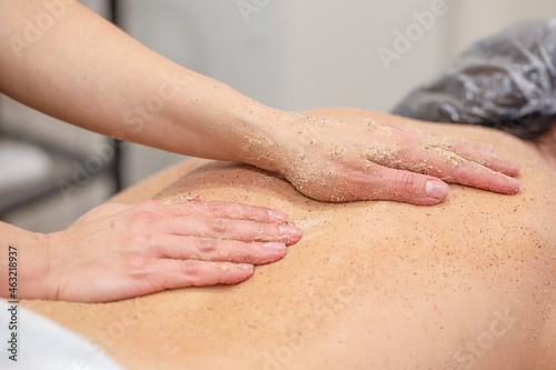 Hands of massagist are scrubbing woman's back photo