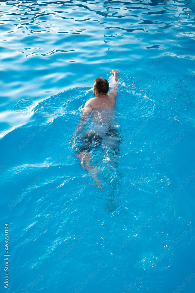 Vertical shot of a Spanish male swimming in a pool.