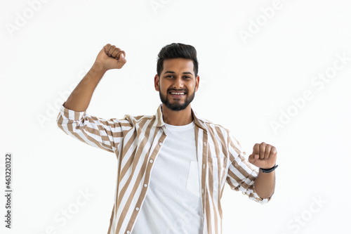 I won. Happy young Indian man gesturing and smiling while standing against white background