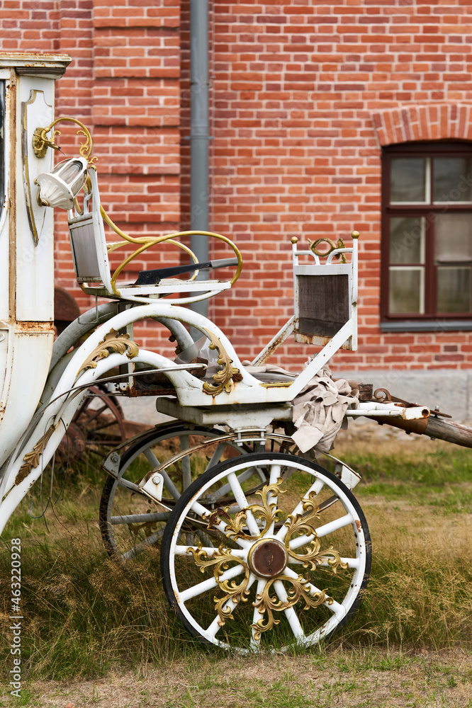 Old white carriage on the background of a red brick building