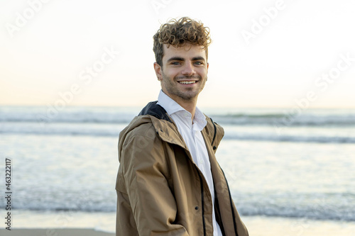 Young boy on the beach smiling with blue eyes walks elegantly dressed at dawn