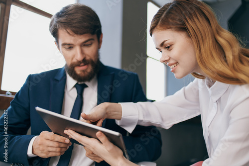 man and woman in business suits looking at the tablet managers professionals