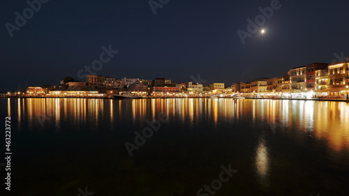 Night skyline cityscape of Chania in Crete, Greece, starry sky, full moon, reflections in sea water