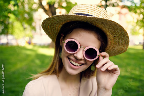 pretty woman sunglasses and a hat in the park green grass