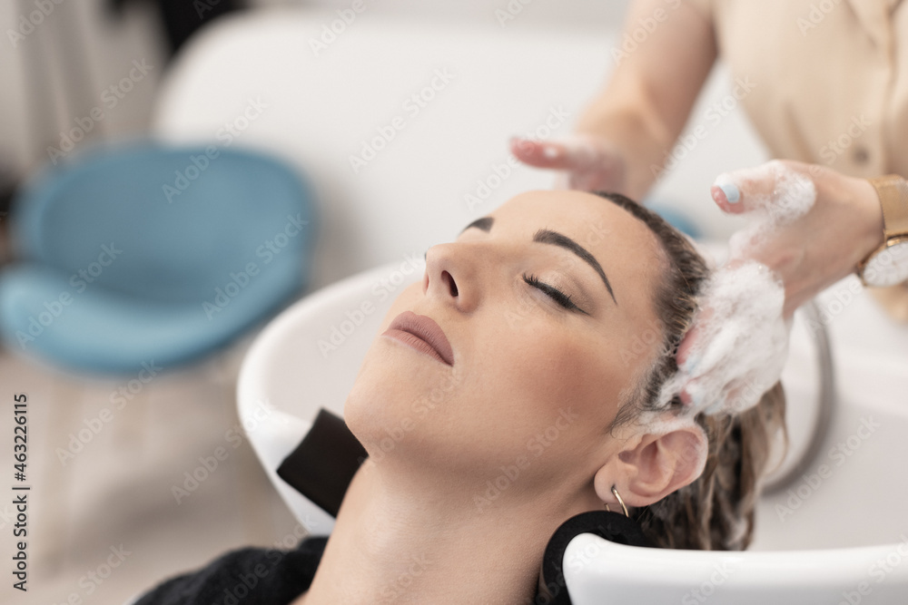 Naklejka premium hairdresser giving a head massage to a caucasian client