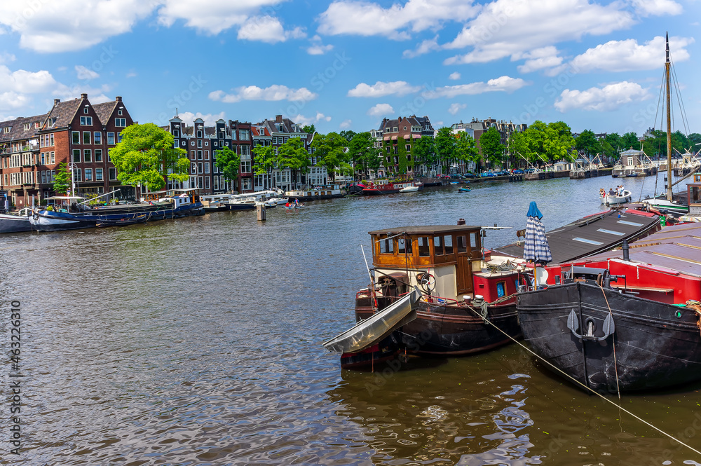 Typical Amsterdam canals with bridges and colorful boat, Netherlands, Europe