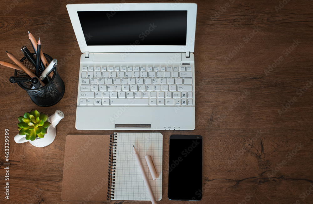 Fototapeta premium Top view of the wooden work table with notebook, notebook, stationery and telephone.