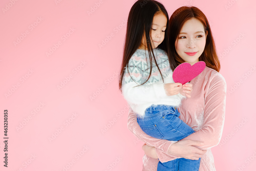 Two portrait beautiful cute asian child girl and woman on pink background with red heart sign holding in hand, valentine day in love concept Two portrait beautiful cute asian child girl and woman on pink background with red heart sign holding in hand, valentine day in love concept