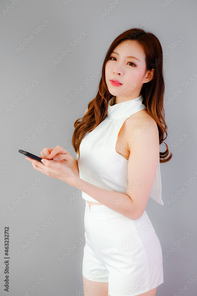 Portrait beautiful asian woman with mobile phone on gray background, emotions action Portrait beautiful asian woman with mobile phone on gray background, emotions action